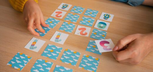 Two people playing a card-matching game on a wooden table, blue cloud-pattern cards laid out in rows.
