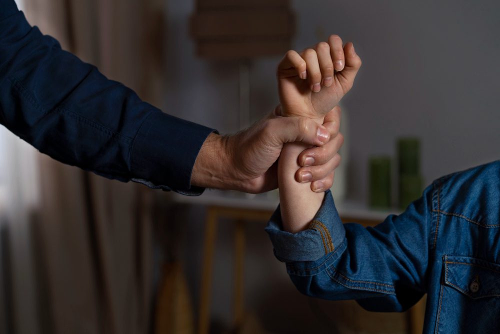 775781 - Kika Fumero | Diario-ABC.Com Adult hand firmly grips a child's forearm during an arm-wrestling-style grip in a home setting, suggesting guidance or restraint.