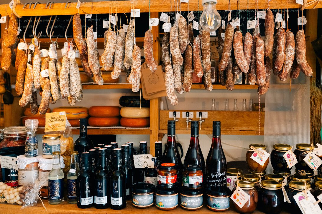 Farm shop of sausages wine and cheeses in the Czech Republic | Diario-ABC.Com Rows of hanging cured sausages and salumi above a market stall, with bottles, jars, and cheeses on the wooden counter below