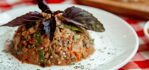 La cocina abulense encuentra nuevas formas de conquistar a vecinos y visitantes - Mounded chopped vegetable and grain salad on a white plate, garnished with purple basil leaves on a red-checked tablecloth.