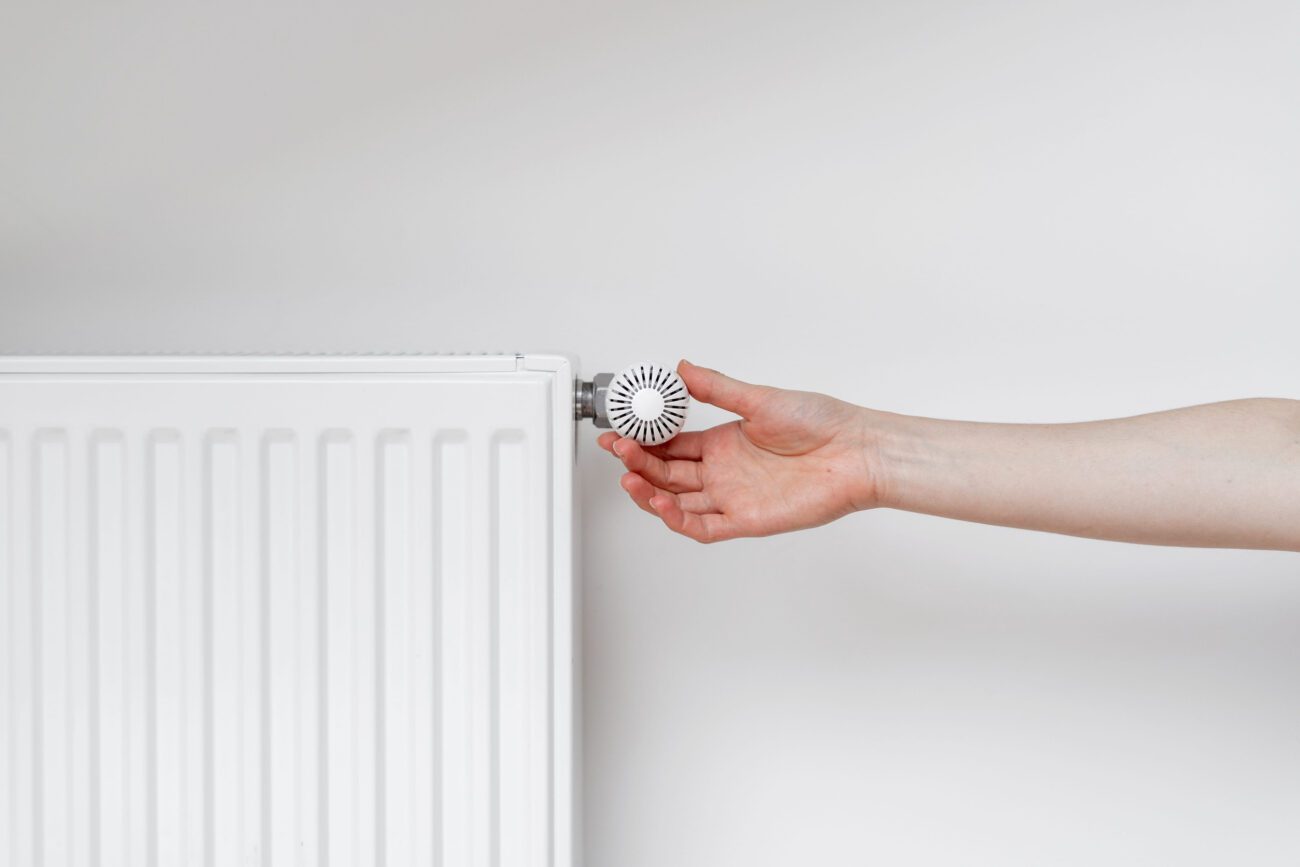 780692 Iteci | Diario-ABC.Com Hand adjusting a white radiator valve knob to control heat output in a room