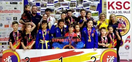 Group of children and coaches on a winners' podium with medals after a martial arts competition in Alcala del Valle.