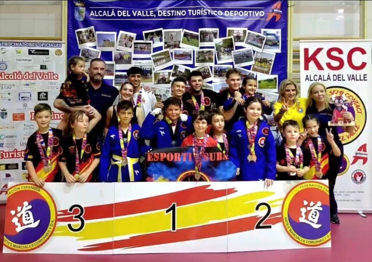 Group of children and coaches on a winners' podium with medals after a martial arts competition in Alcala del Valle.