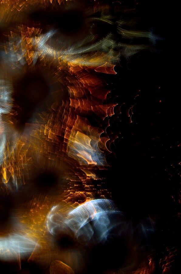 Génesis Fundación Mutua Levante - IP | Diario-ABC.Com Abstract composition of blurred, colorful light orbs and streaks in orange, gold, blue on a dark background, creating a moody, dreamy pattern.