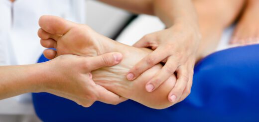 Physical therapist holds and massaging a client's bare foot during therapy session.